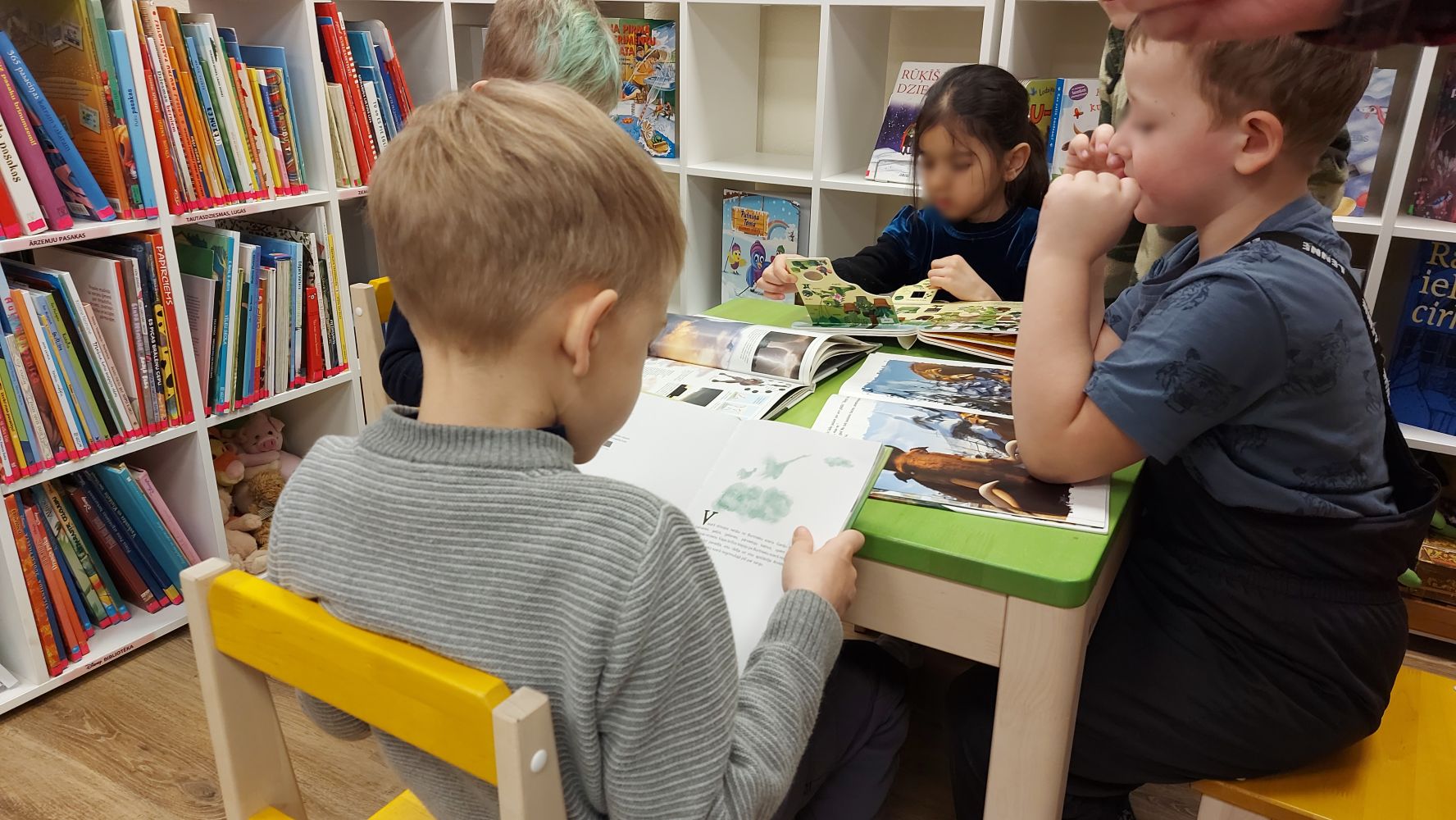 Bērni iepazīstas ar bibliotēkas krājumā esošajām grāmatām.