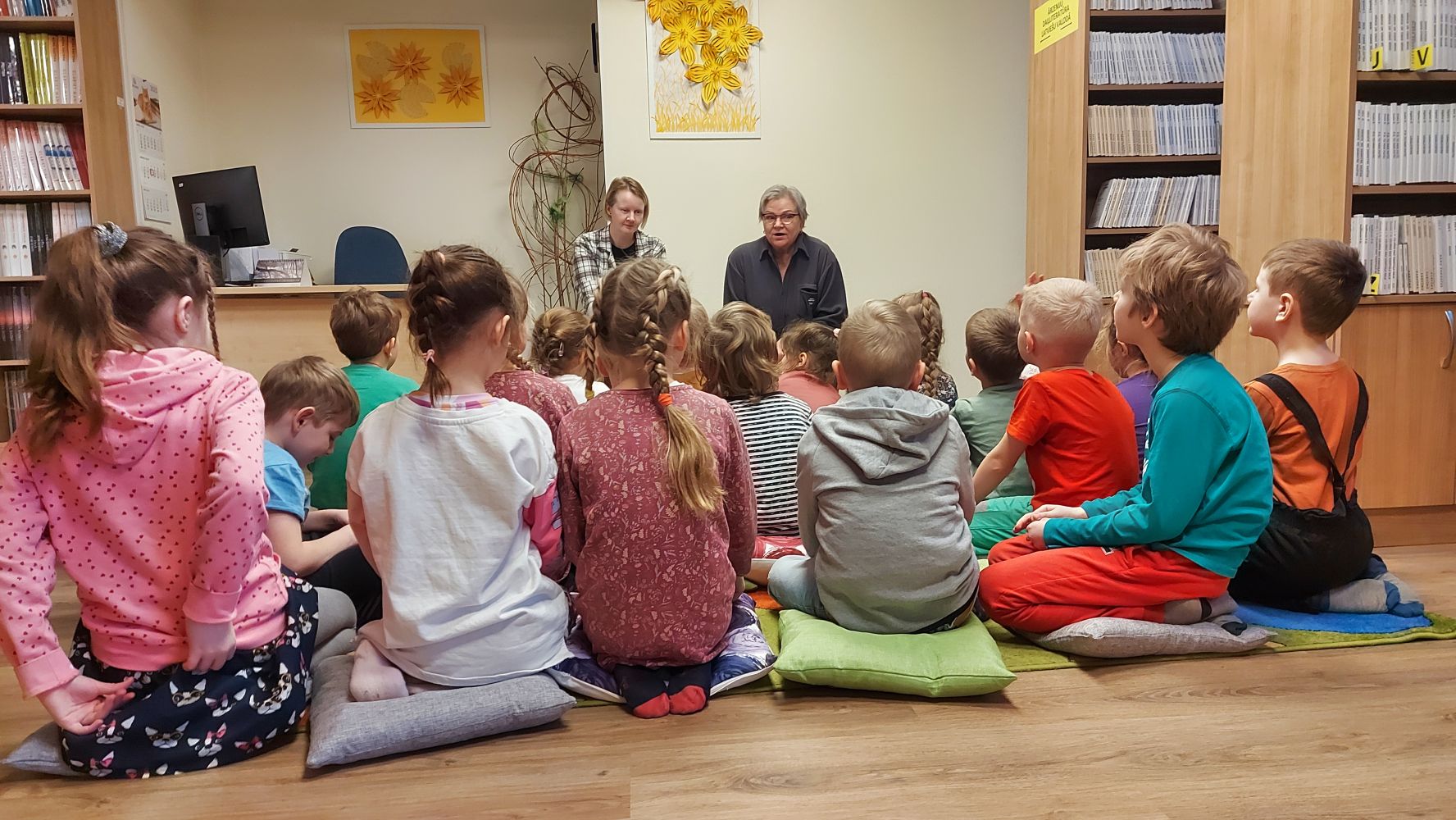 Bērni klausās bibliotekāru lasījumā