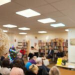 Tuvplānā Ziemassvētku rotājums. Fonā pasākuma apmeklētāji